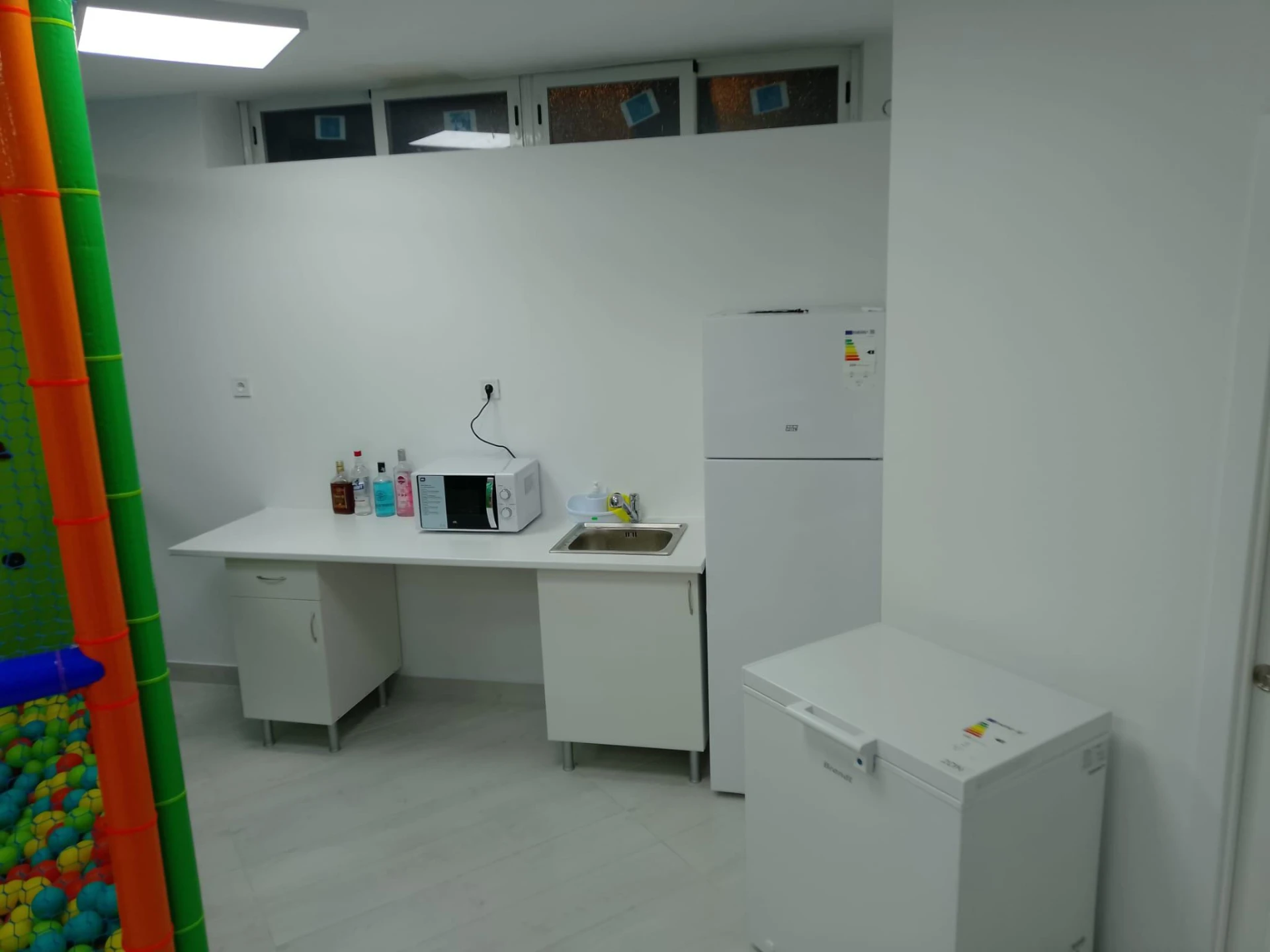Zona de office con microondas, fregadero y nevera en la sala de cumpleaños de Vallecas